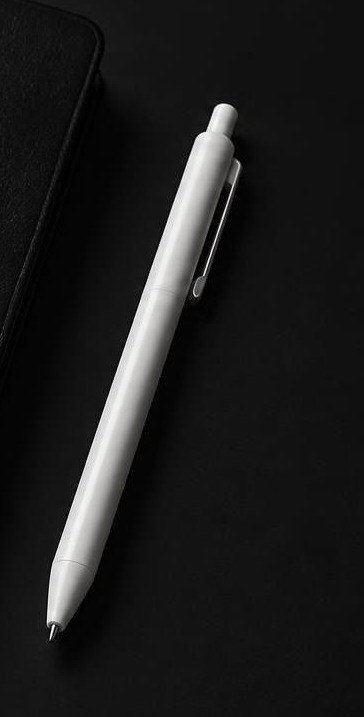 A clean white gel pen against a near-black surface.